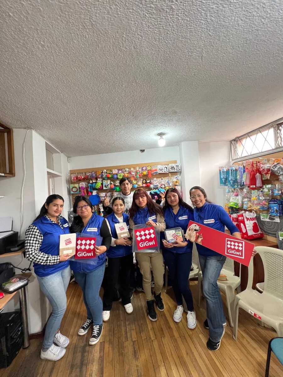 Equipo de MascotaModa con chalecos azules sosteniendo kits y carteles de GiGwi en su local